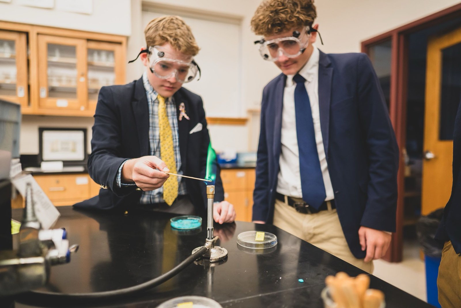 Two Salesianum students in safety goggles and blazers running a lab experiment
