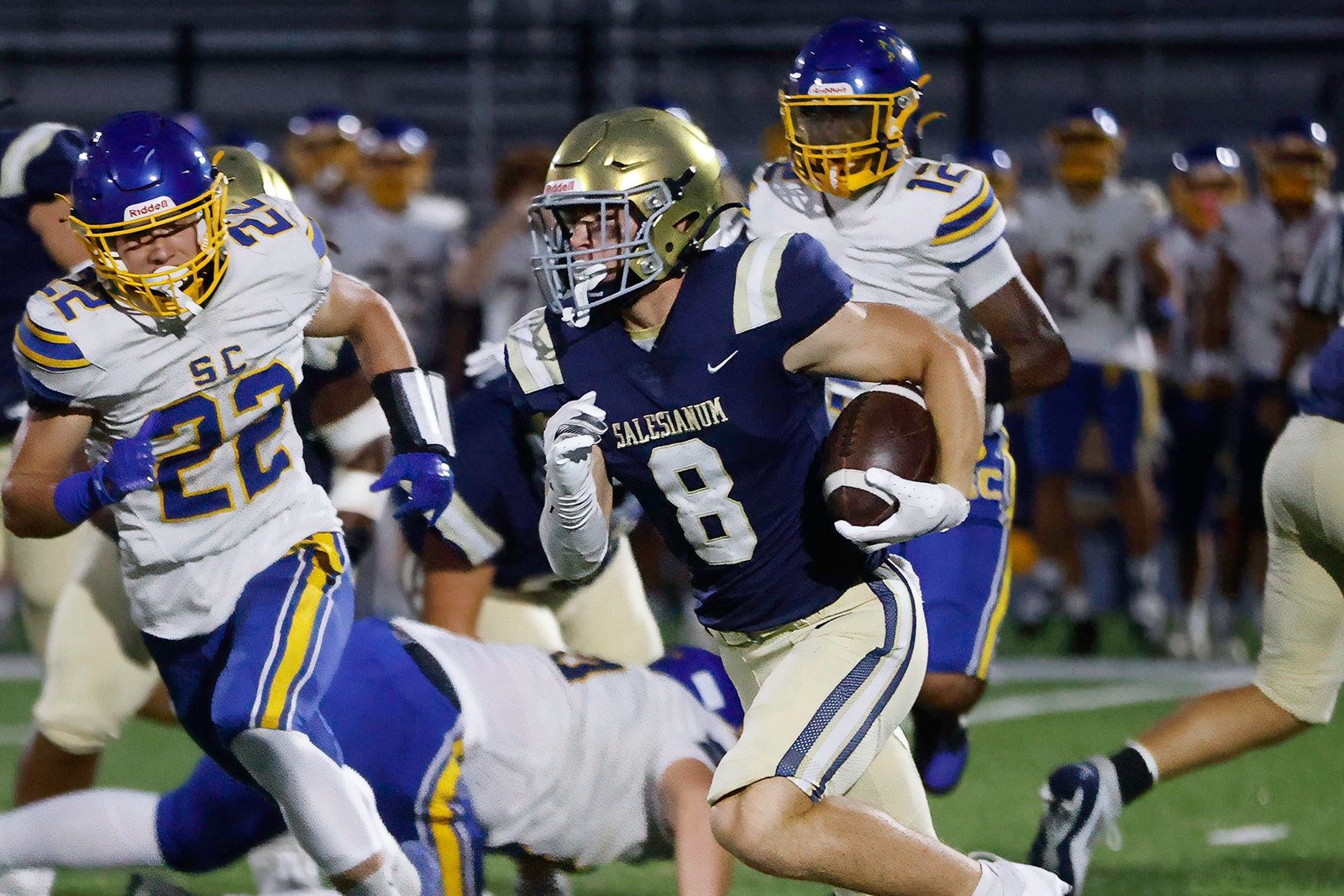 Salesianum football players in navy driving through a tackle