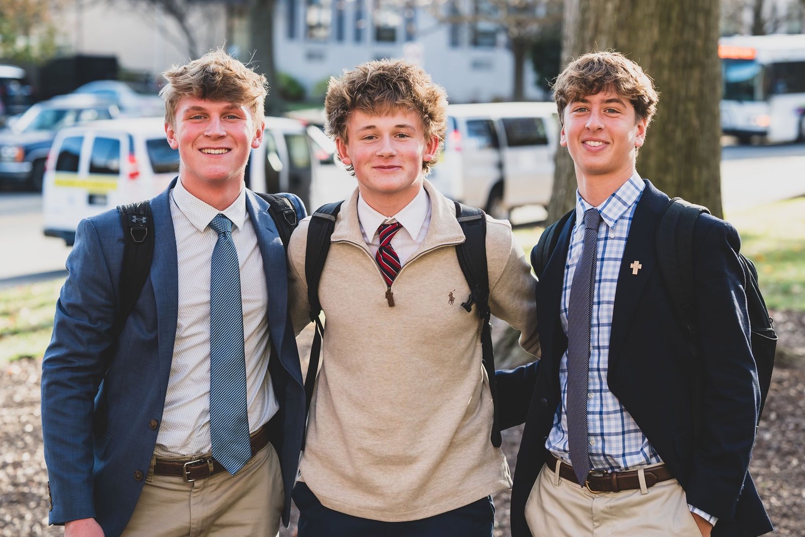 Three Salesianum students in blazers smiling outside the school